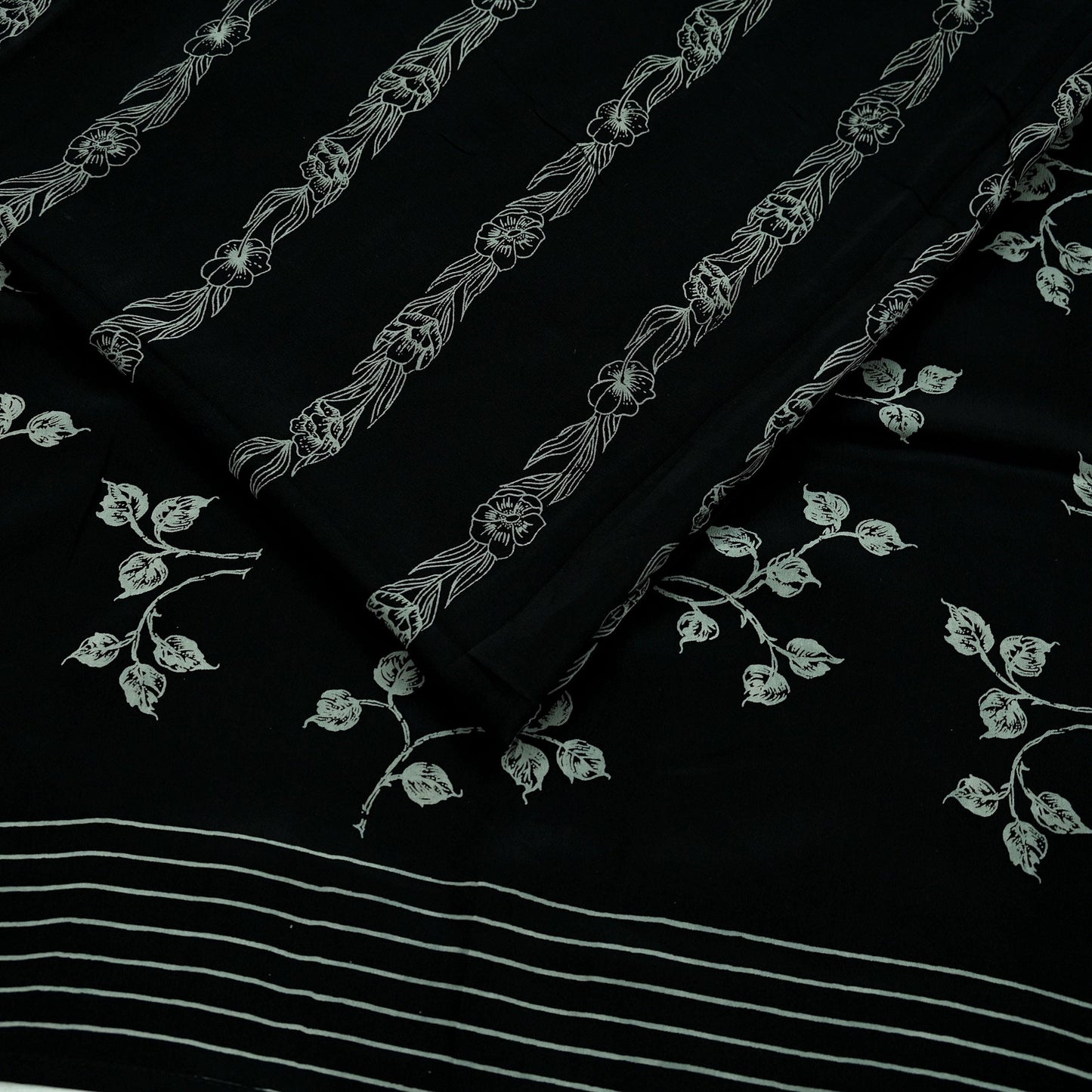 Black pure crepe silk saree fabric with white floral print on a black background
