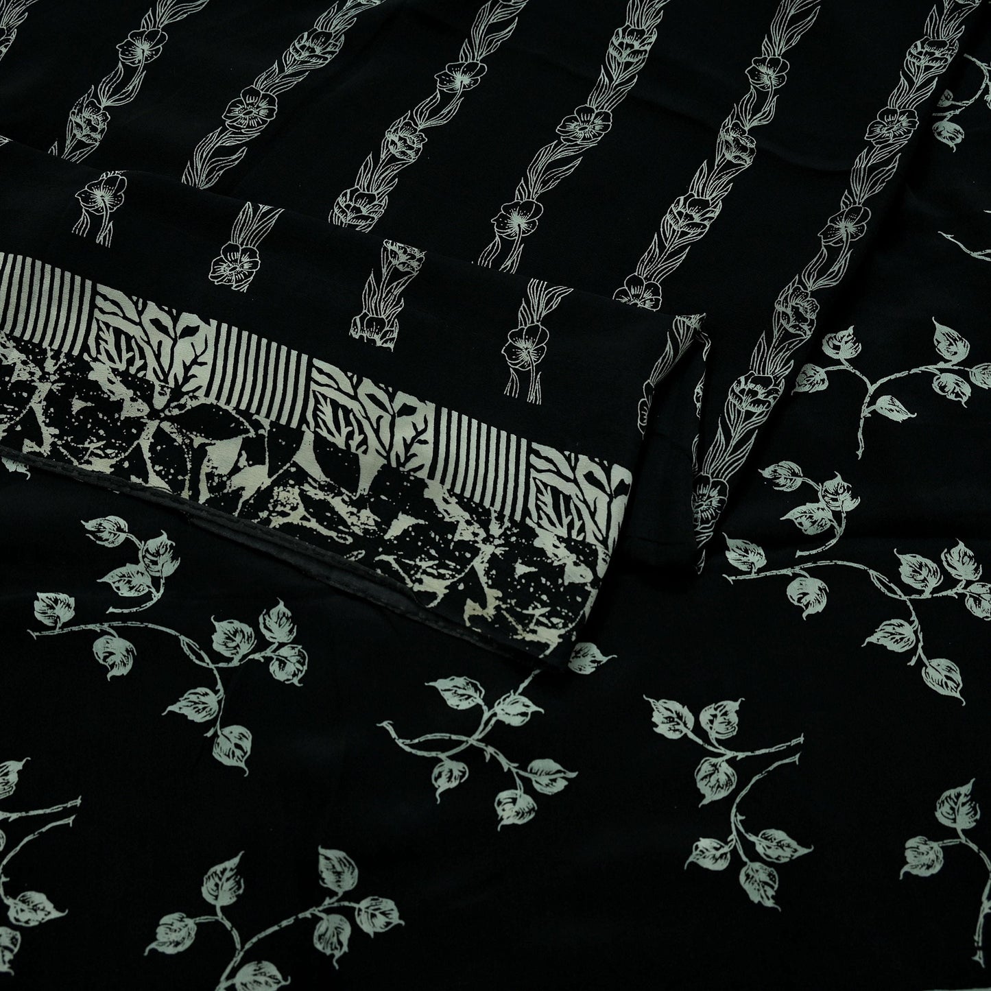 Black pure crepe silk saree fabric with white floral patterns on a black background