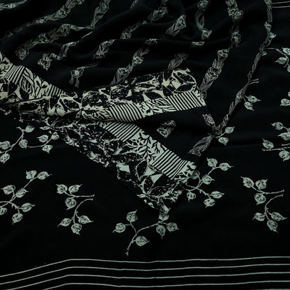 Close-up of black pure crepe silk saree fabric with white floral print on a dark background
