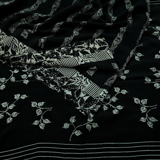 Close-up of black pure crepe silk saree fabric with white floral print on a dark background