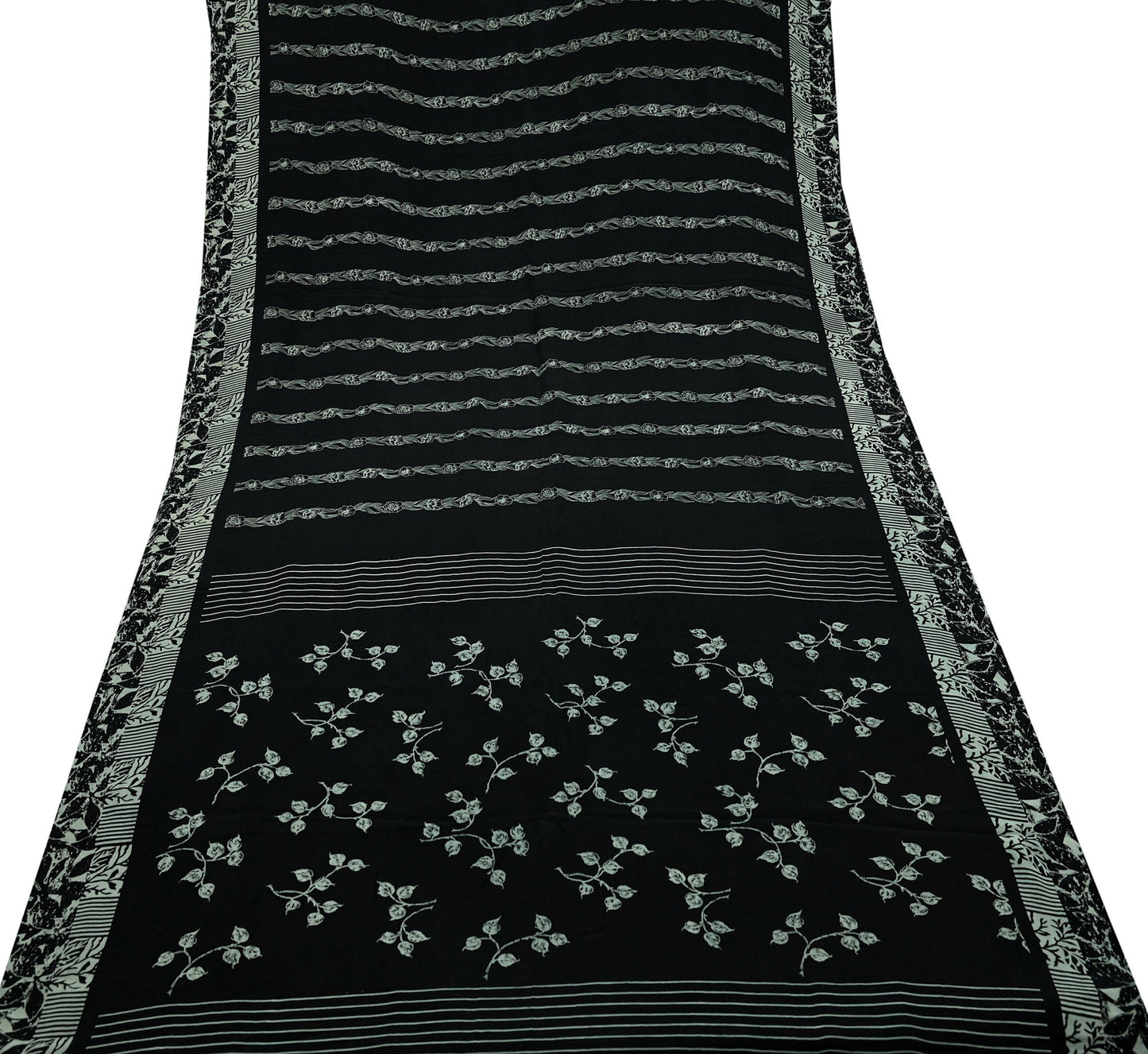 Black pure crepe silk saree fabric with white floral patterns and decorative borders on a white background