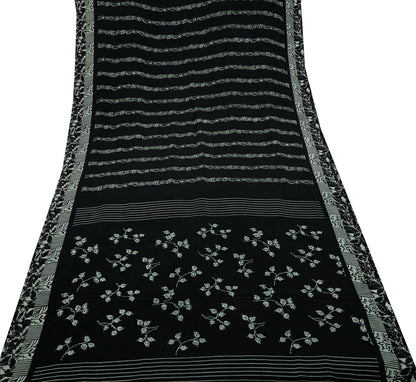 Black pure crepe silk saree fabric with white floral patterns and decorative borders on a white background
