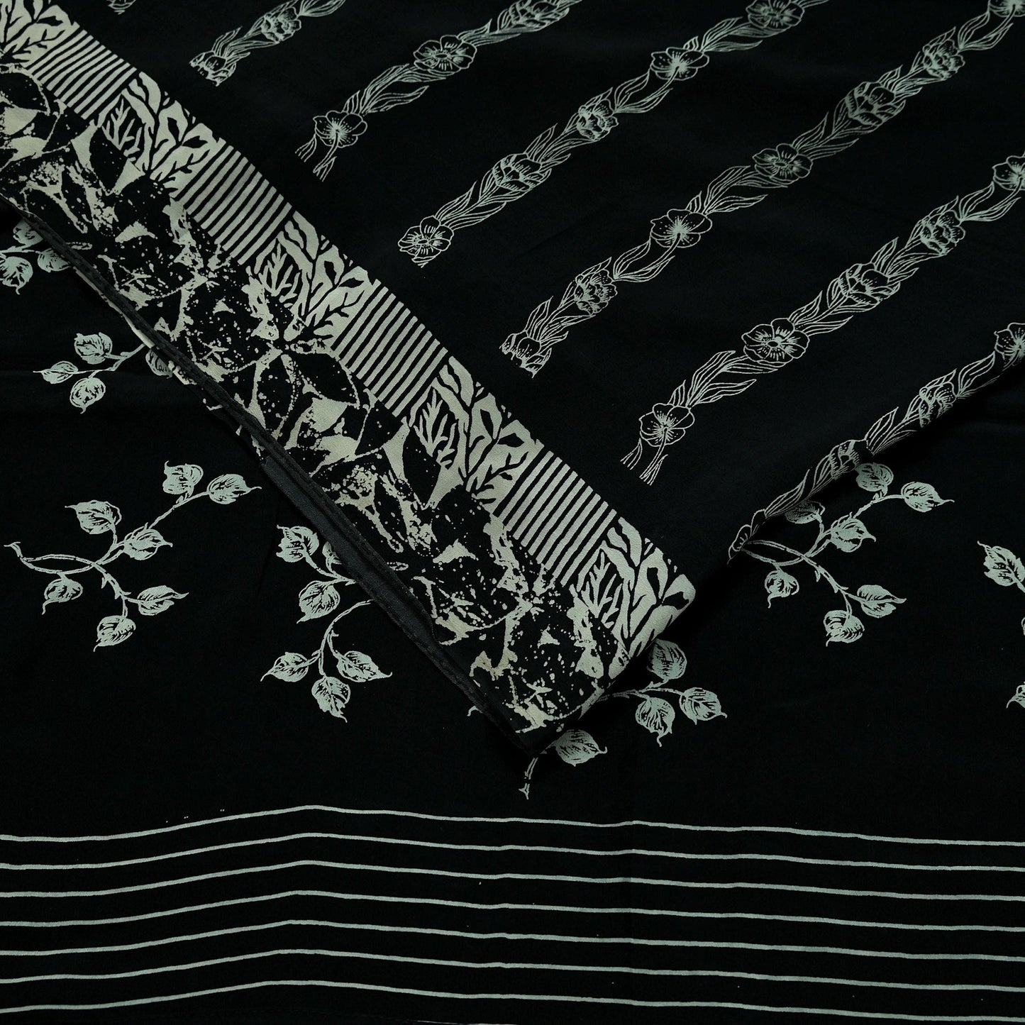 Decorative pure crepe silk saree fabric with floral and striped patterns on a black background