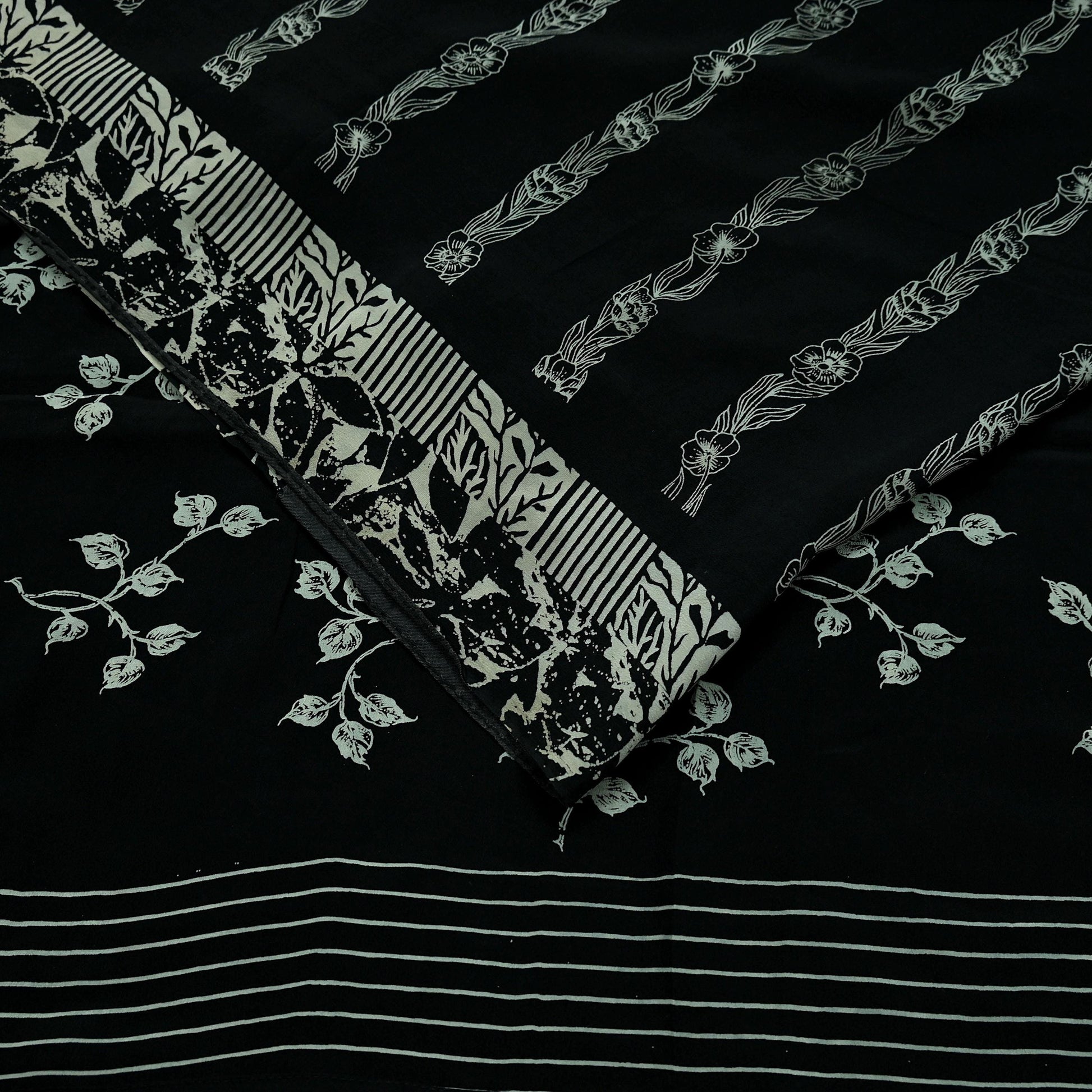 Decorative pure crepe silk saree fabric with floral and striped patterns on a black background