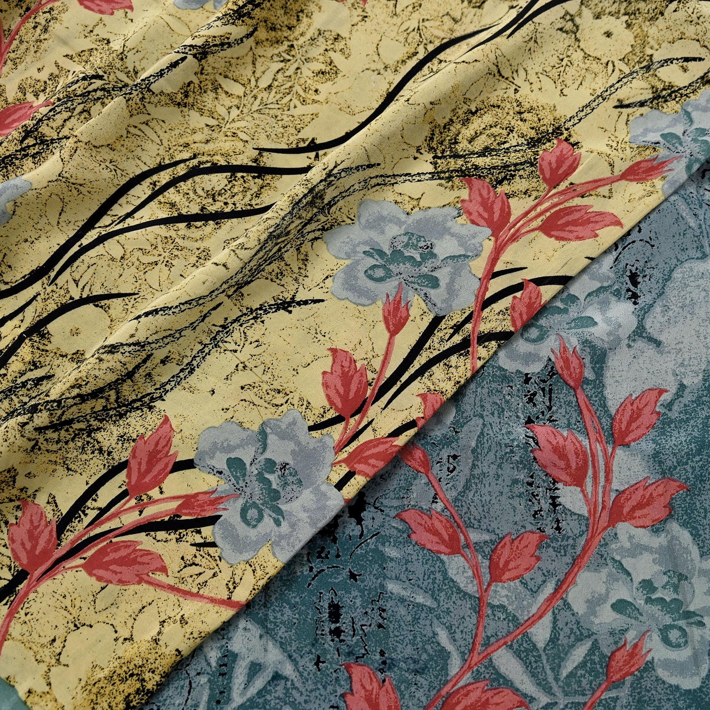 Two floral patterns of the same printed silk saree shown side-by-side, one gold and black, the other blue and red.