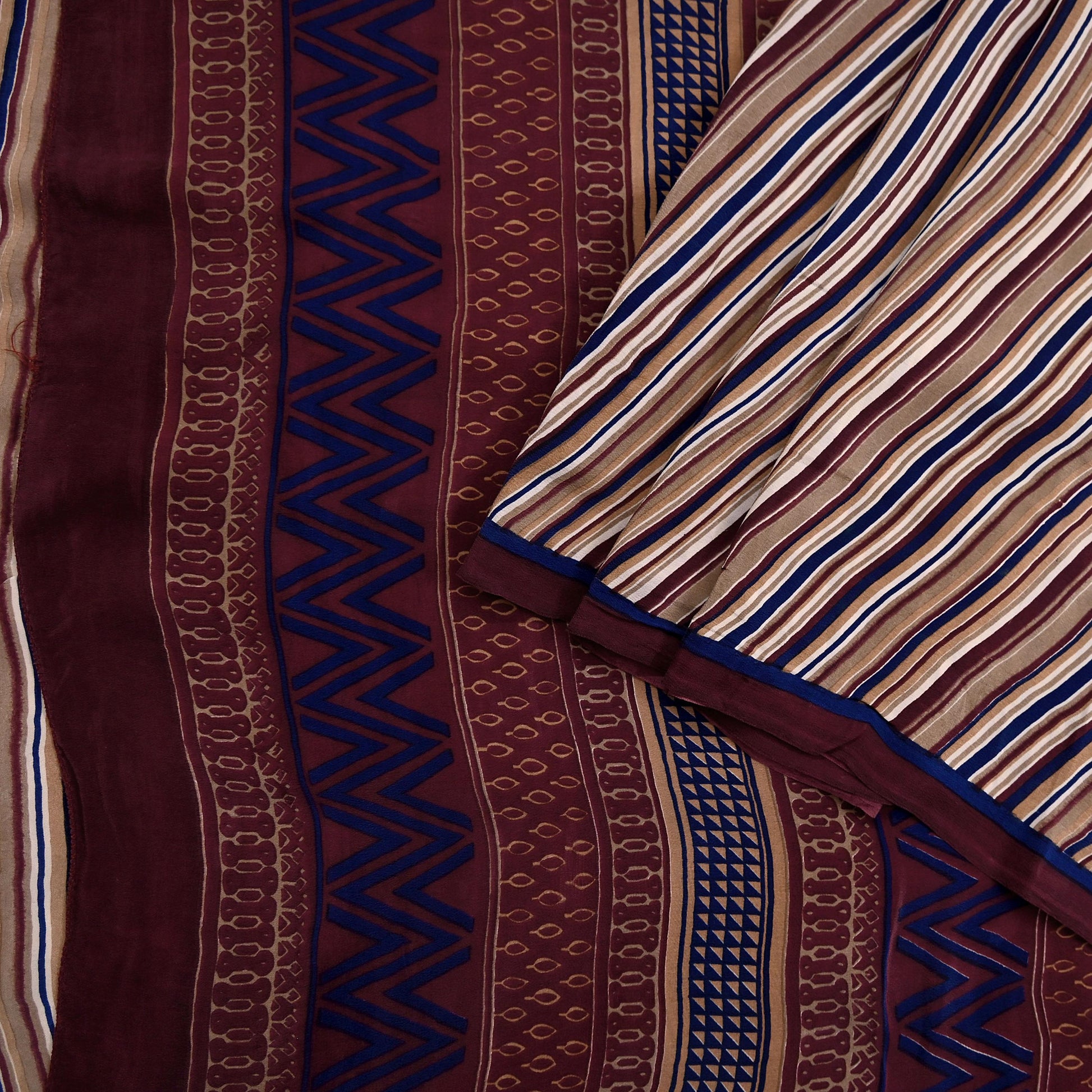 Close-up of patterned fabric with zigzag and stripe designs in brown, blue, and beige.