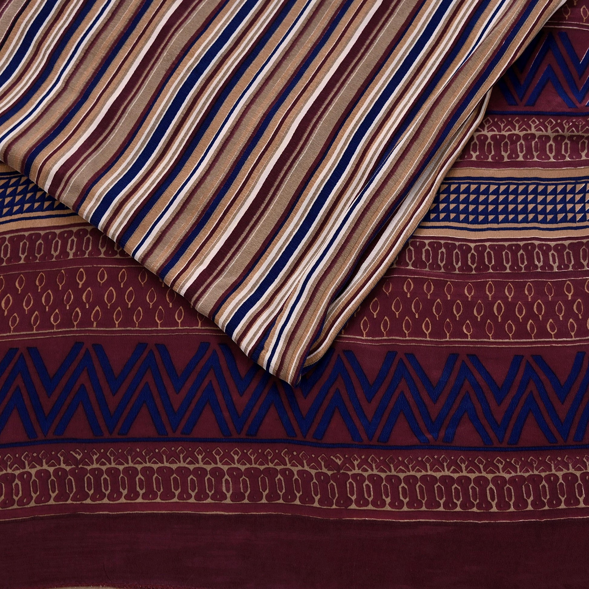 Close-up of patterned fabric with stripes and geometric designs in brown, blue, and beige.