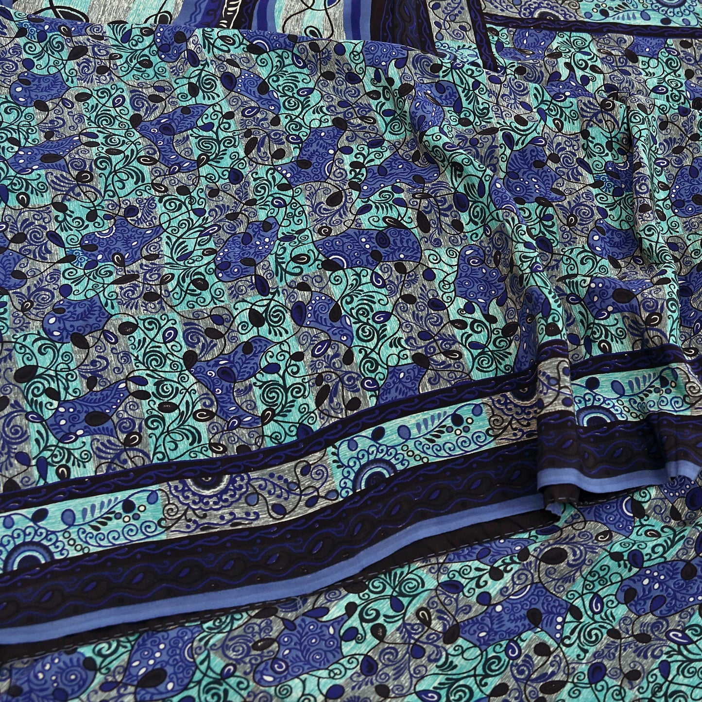 Close-up of a printed pure crepe silk saree fabric with blue and green design