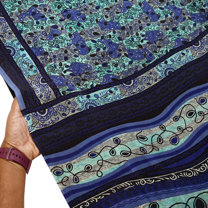 Close-up of a pure crepe silk saree fabric with blue and green pattern, held by a hand.