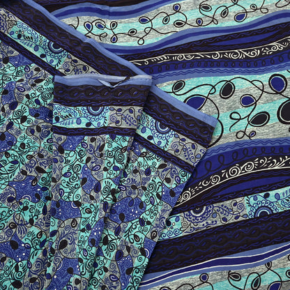 Close-up of a patterned pure crepe silk saree fabric with blue, green, and black colors.