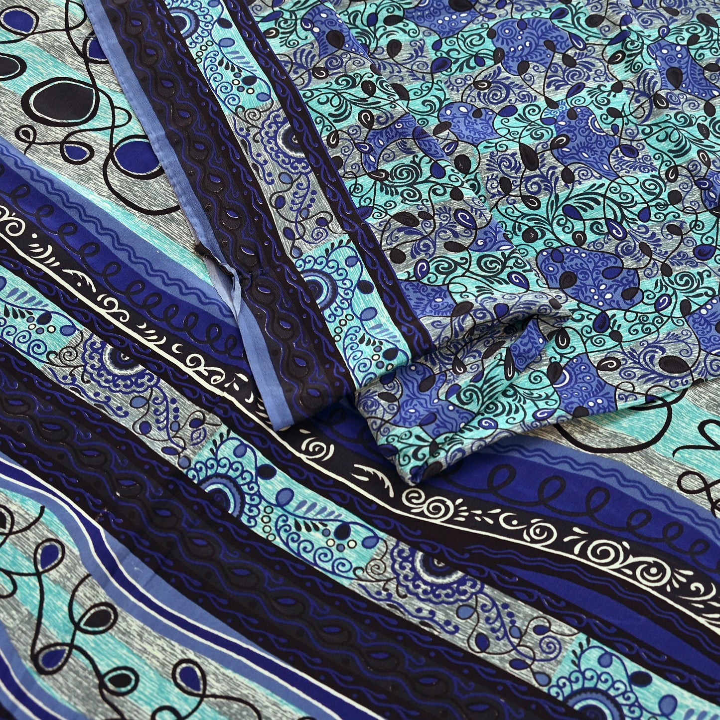 Close-up of patterned pure crepe silk saree fabric with blue, black, and green colors.