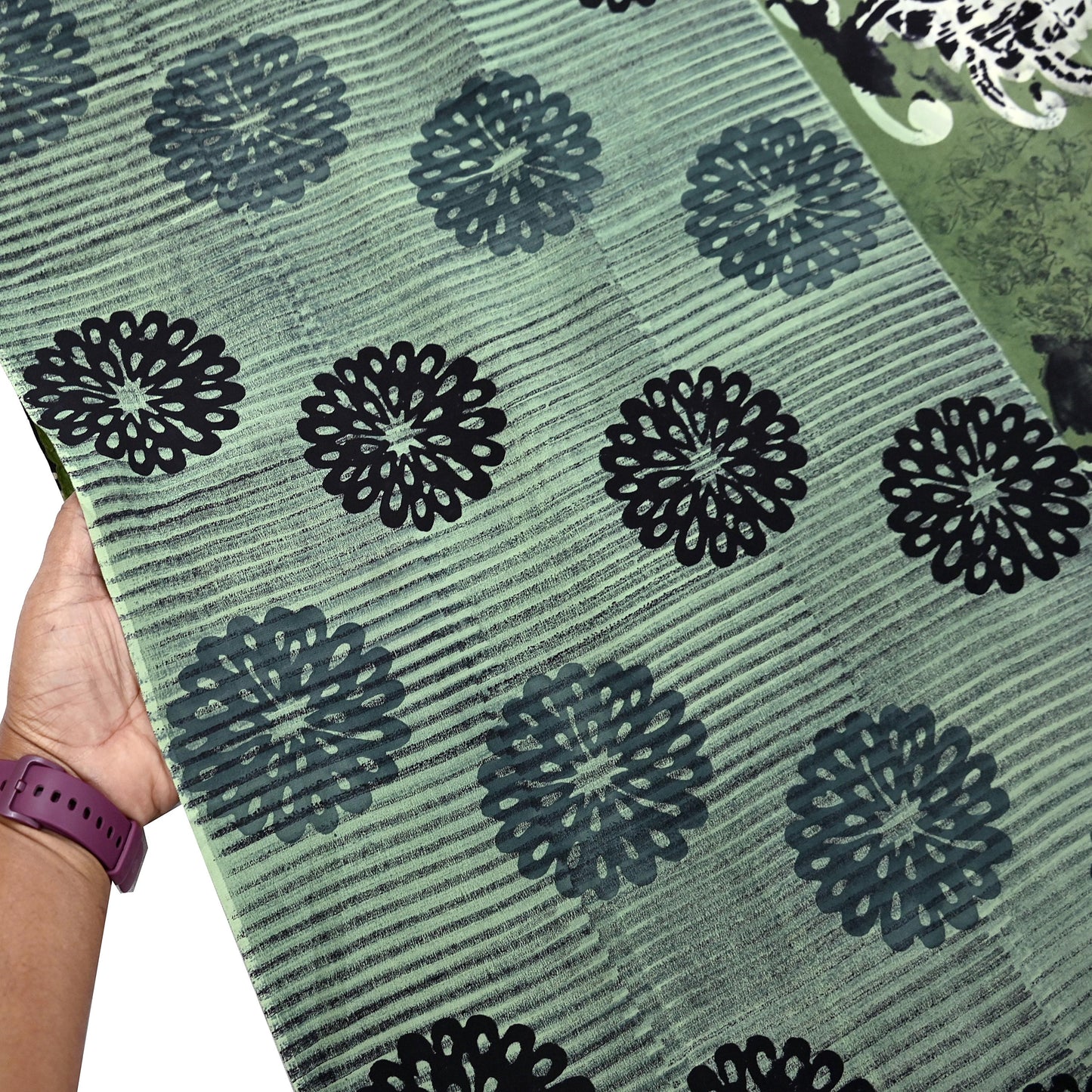 Green pure crepe silk saree with black floral patterns held by a hand