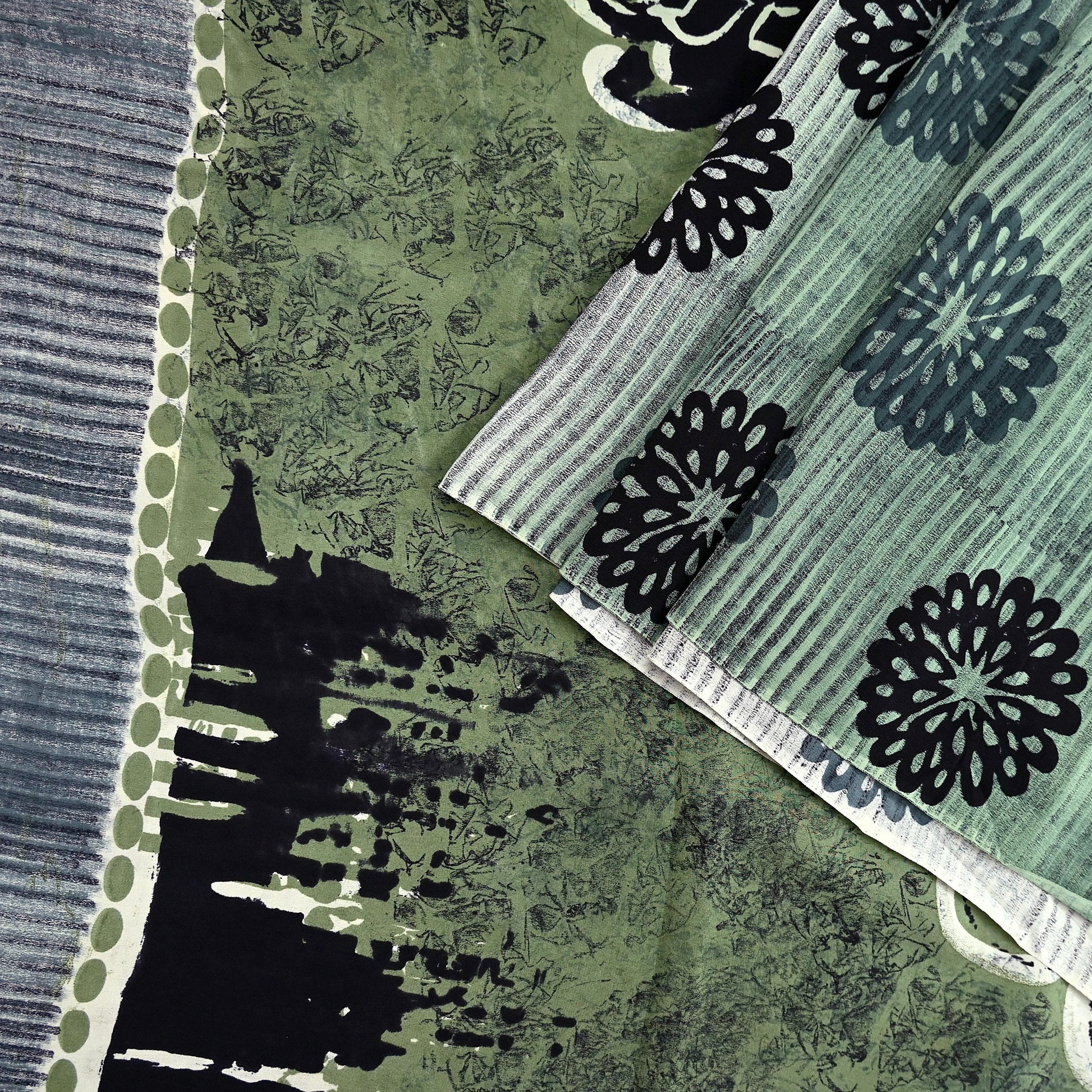Close-up of vintage pure crepe silk saree fabric with black floral patterns on a green and gray background