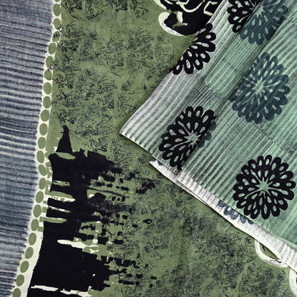 Close-up of vintage pure crepe silk saree fabric with black floral patterns on a green and gray background