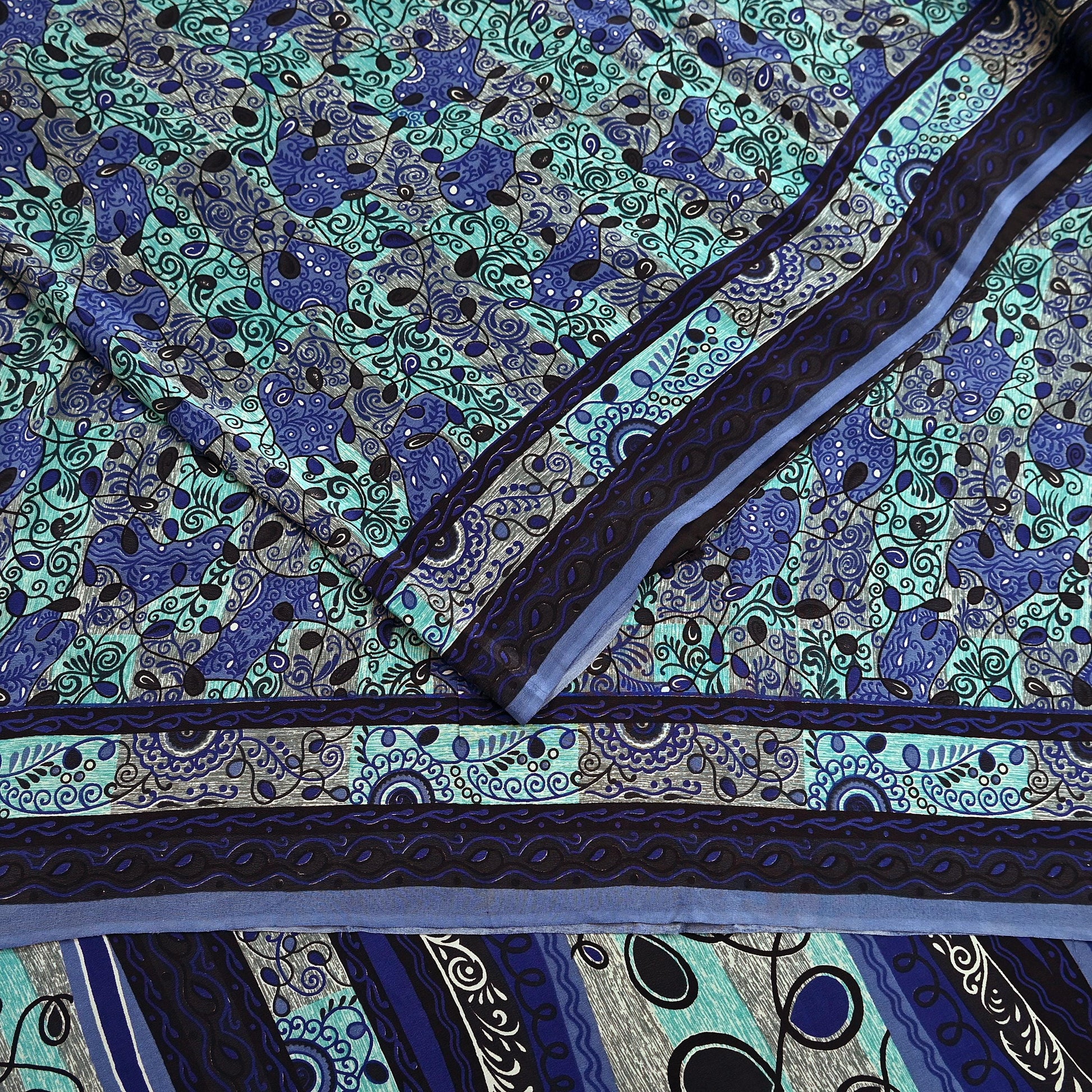 Close-up of a patterned pure crepe silk saree fabric with blue and green design
