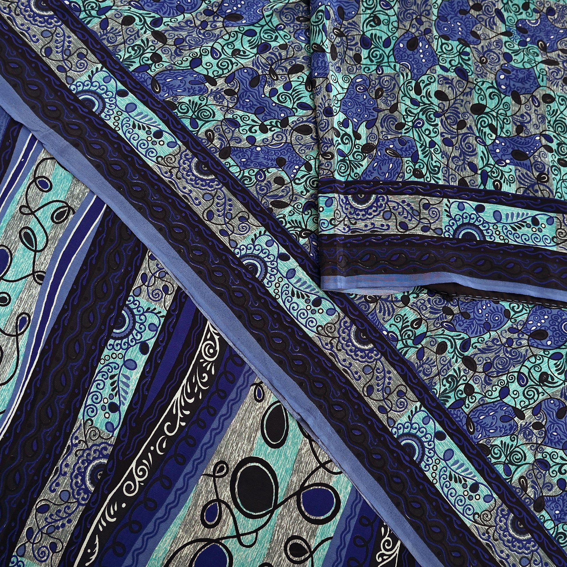 Close-up of a patterned pure crepe silk saree fabric with blue and green design