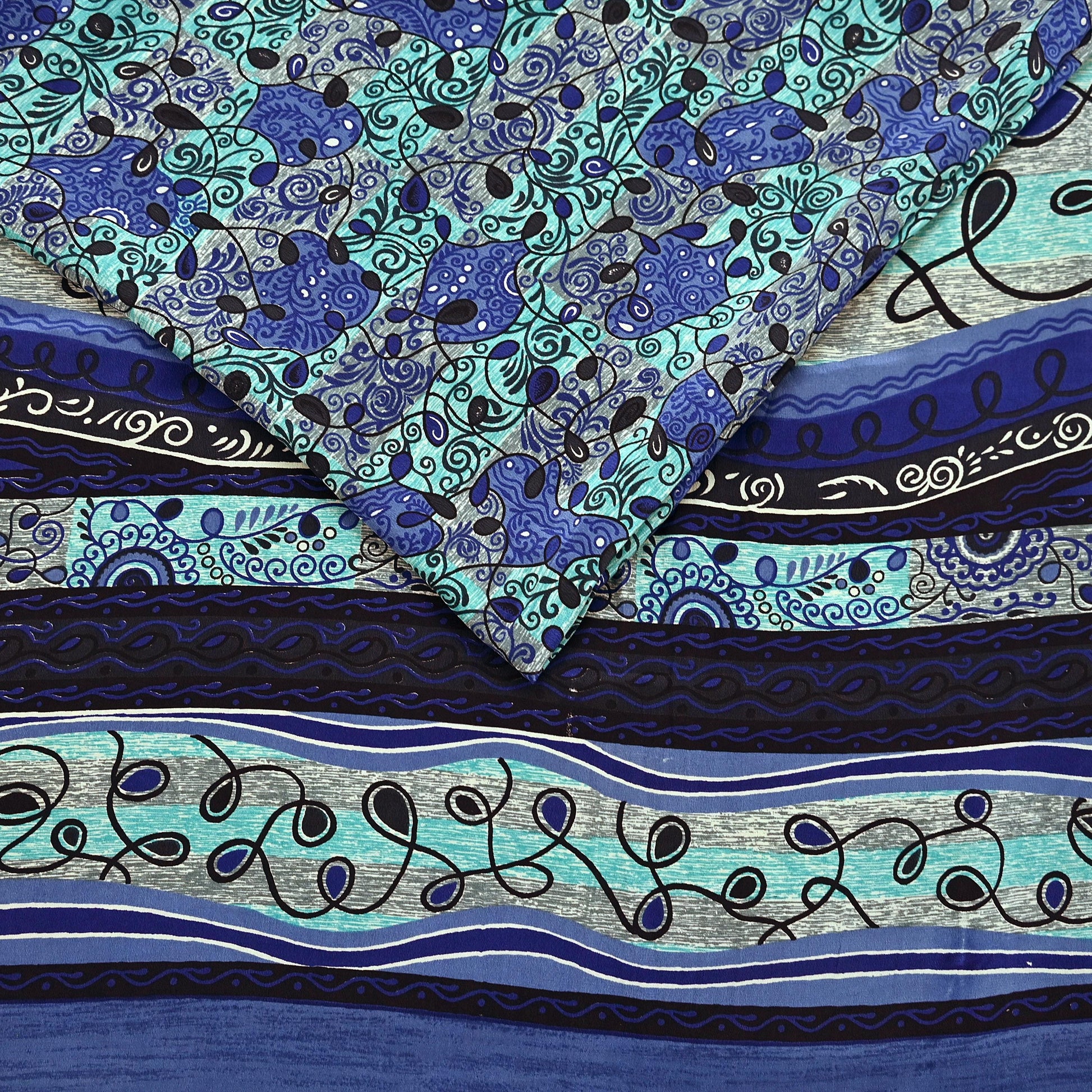 Creative shot of a blue and green pure crepe silk saree fabric with intricate prints.