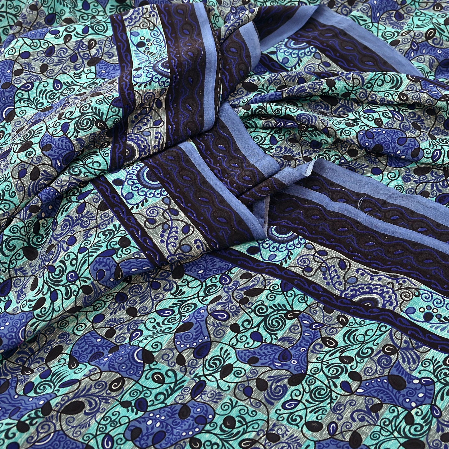 Patterned pure crepe silk saree fabric with blue and green design on a green background