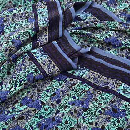 Patterned pure crepe silk saree fabric with blue and green design on a green background