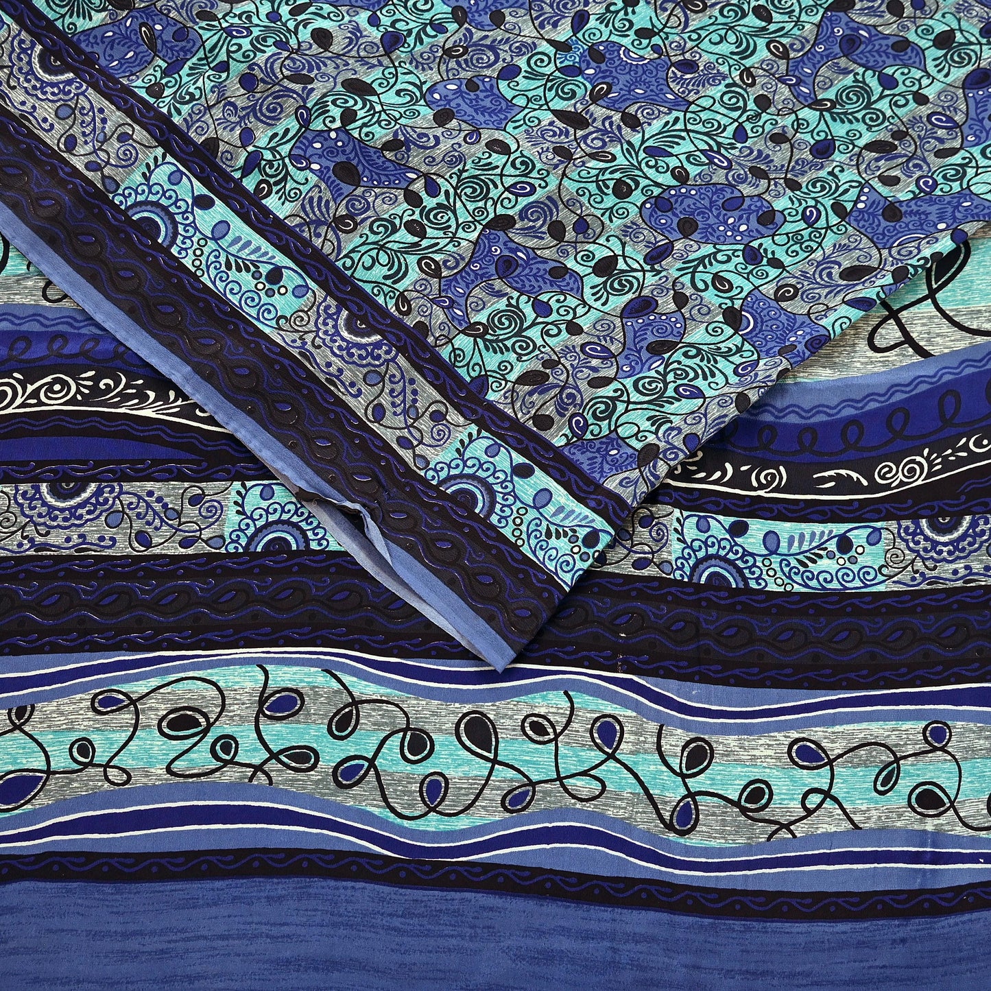 Patterned pure crepe silk saree fabric with blue and green design on a blue background