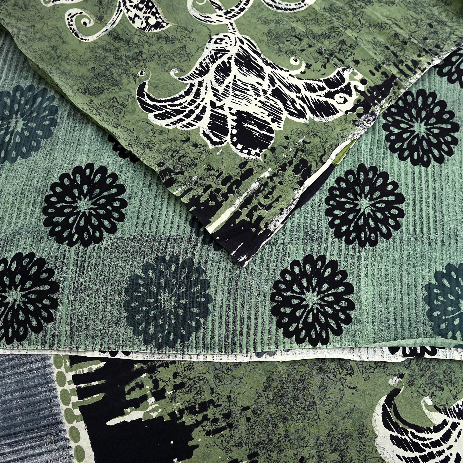 Close-up of a green pure crepe silk saree fabric with black floral patterns