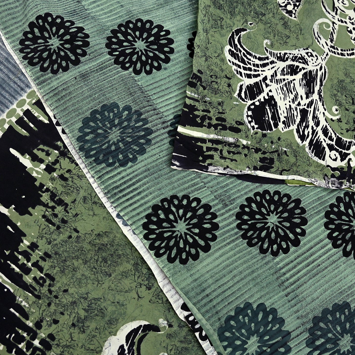 Close-up of green silk saree fabric with black floral patterns