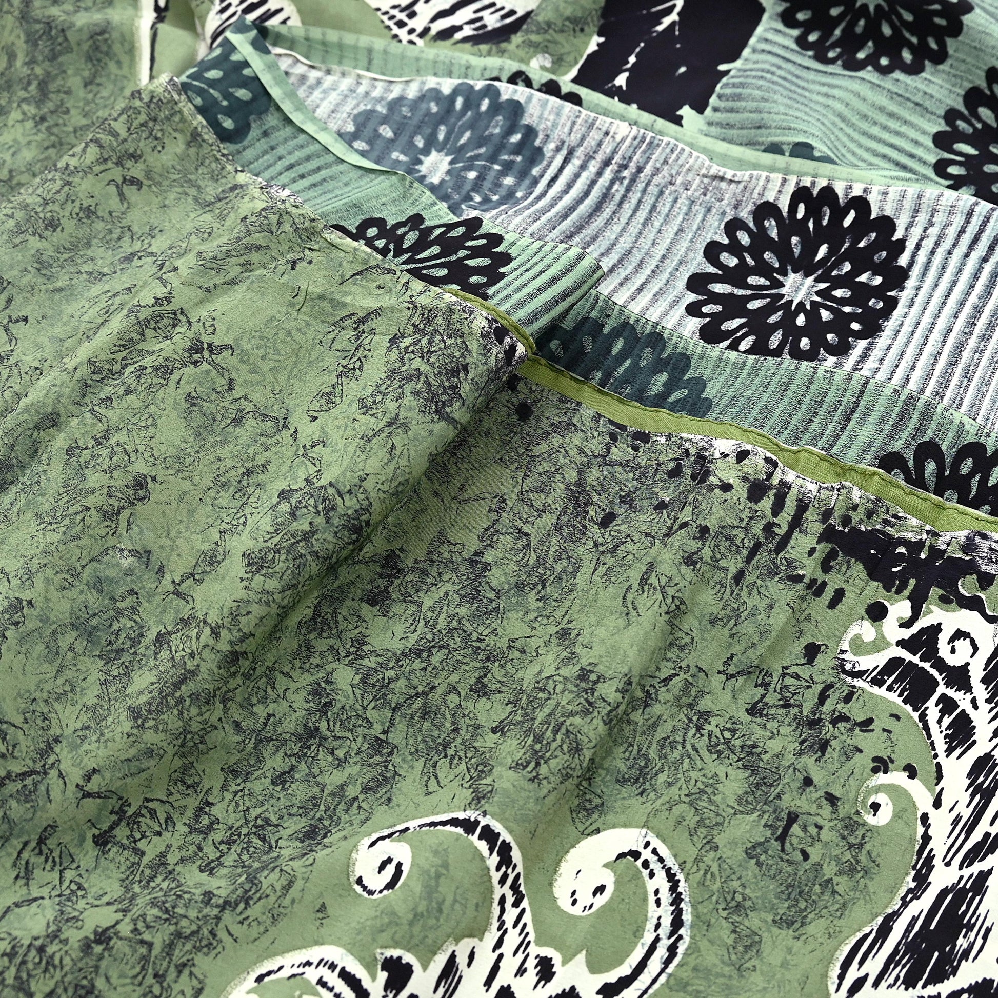 Close-up of a green pure crepe silk saree fabric with black floral patterns