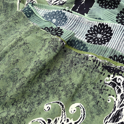 Close-up of a green pure crepe silk saree fabric with black floral patterns