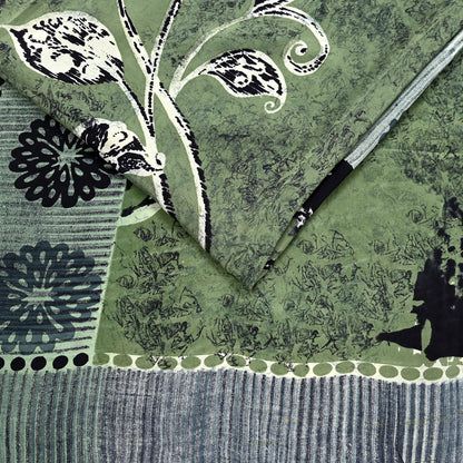 Decorative silk saree fabric with black floral patterns on a green background
