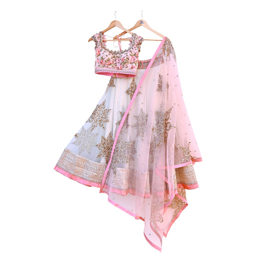 Traditional Indian outfit with a floral blouse and white saree with gold patterns on a white background